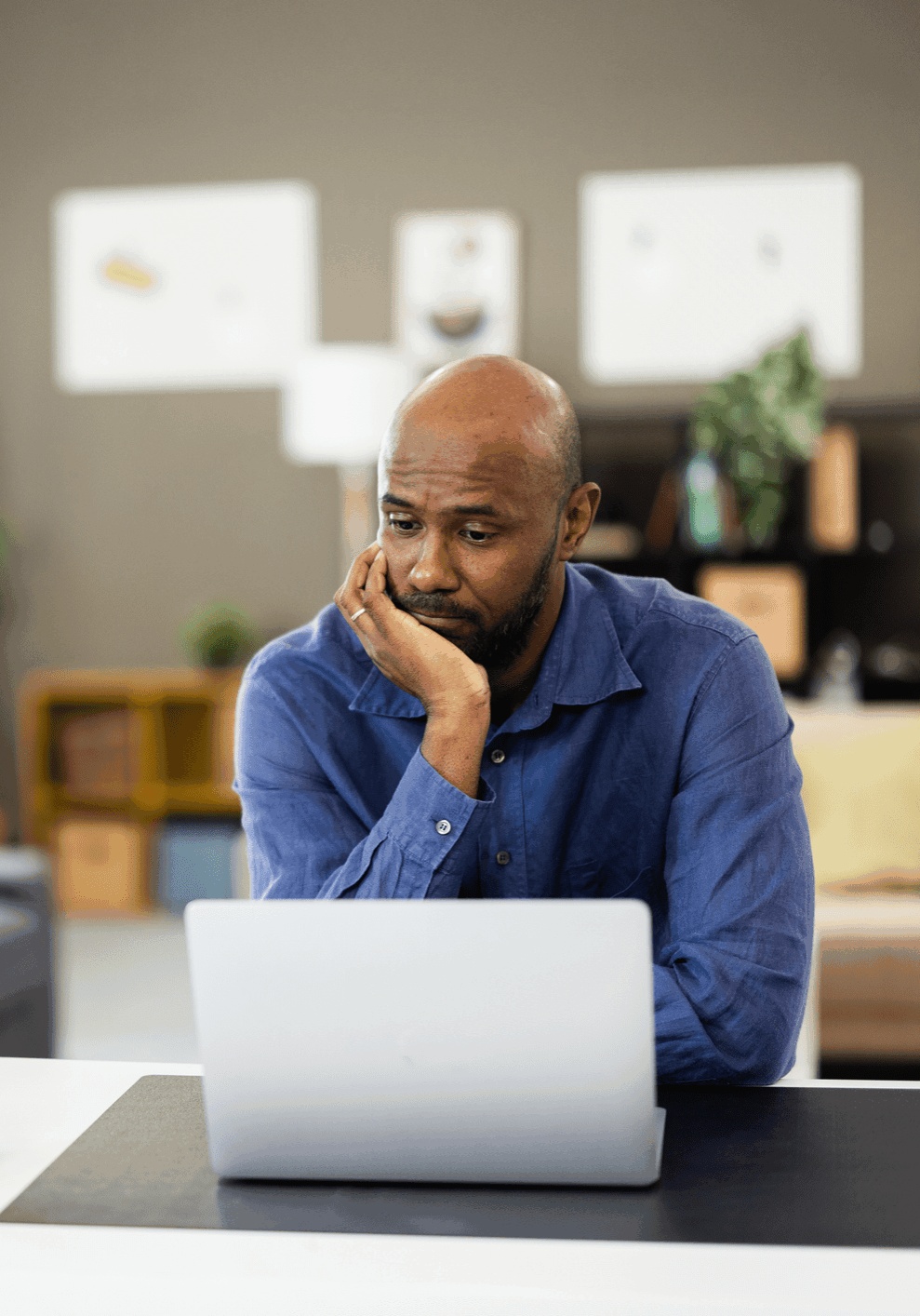 Man looking worried while using a laptop at home.